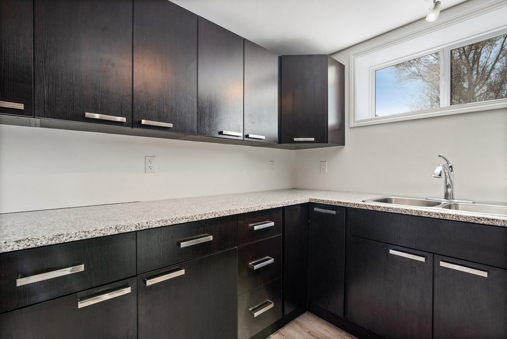 an empty kitchen with black cabinets and a sink