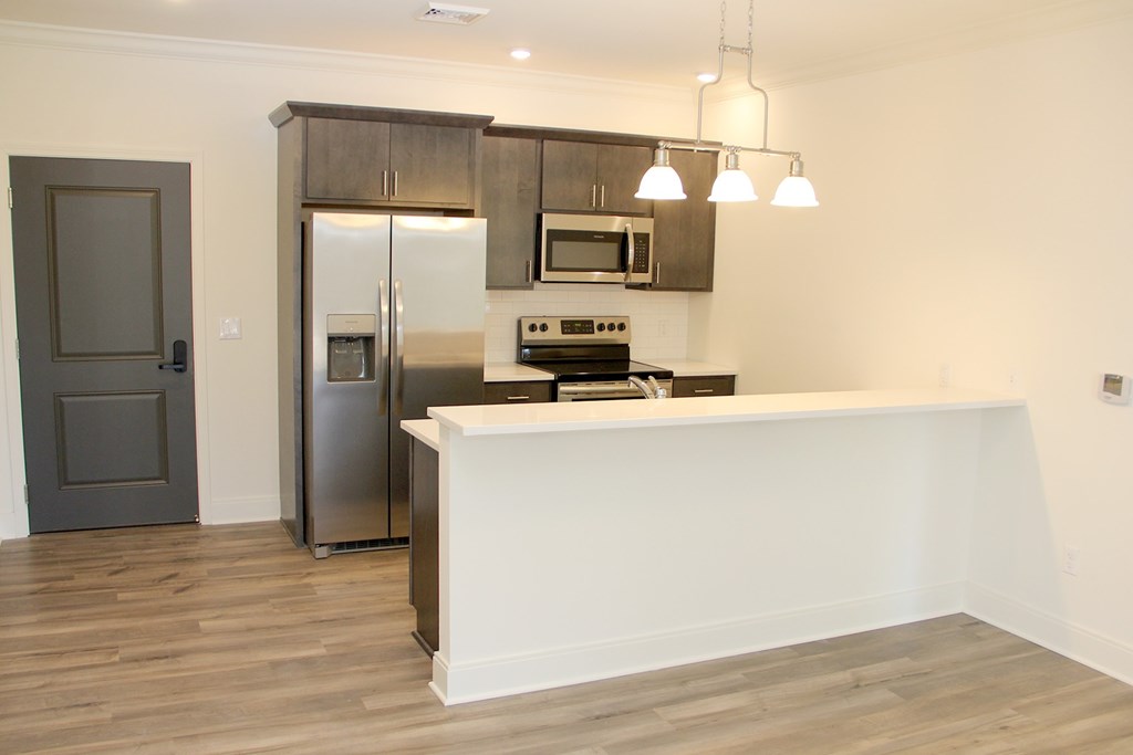a kitchen with a white counter top and a stainless steel refrigerator