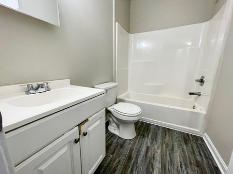 A white bathroom with a toilet, sink, and bathtub.