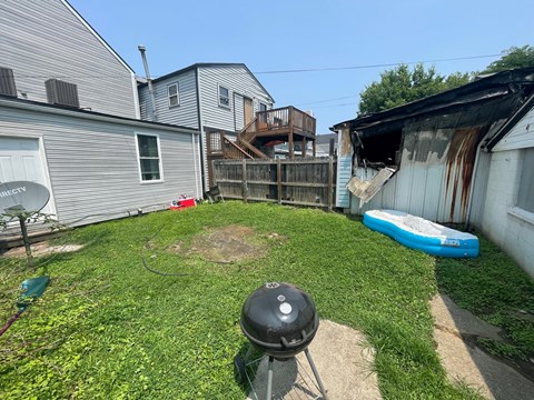 A backyard with a BBQ grill and a blue kayak.