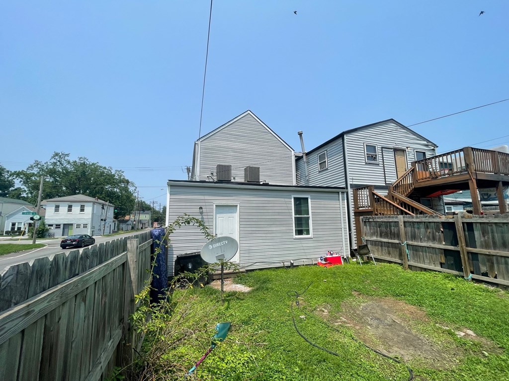 A house with a grey siding and a white door is surrounded by a wooden fence.