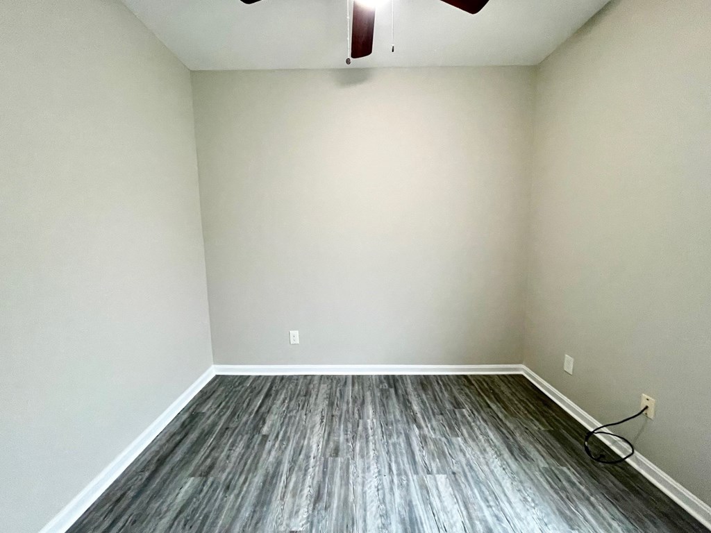A room with a ceiling fan and wooden flooring.