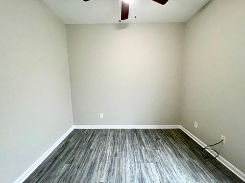 A room with a ceiling fan and wooden flooring.