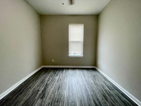 A room with a window and wooden flooring.