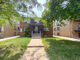 the entrance to a brick building with a sidewalk and grass