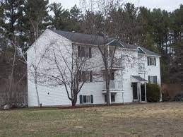 A white house with a bare tree in front.