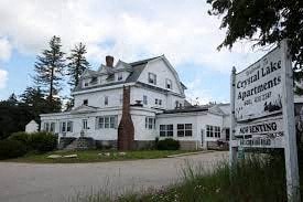 A white building with a sign in front that says Coyall Lake Apartments.