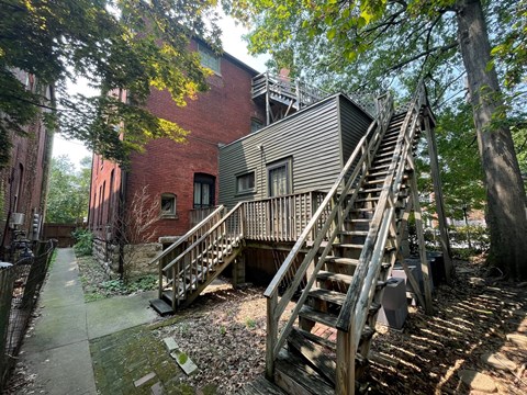 the exterior of a brick building with stairs and a deck