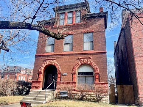 an old brick building with a tree in front of it