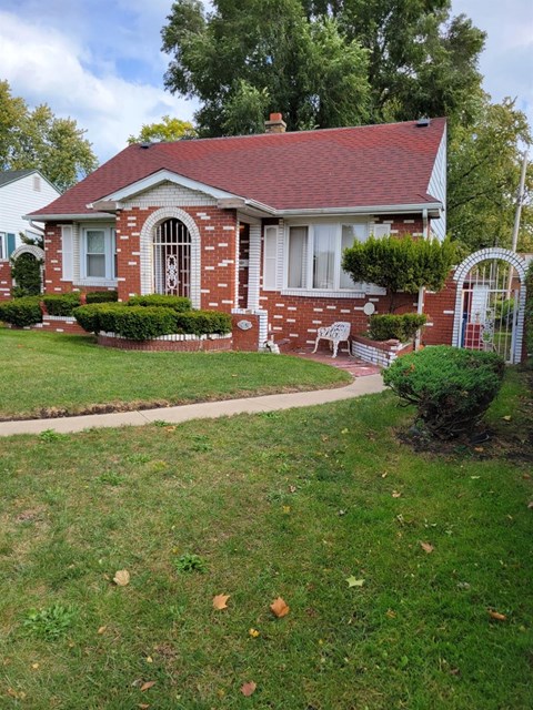 a small brick house with a lawn in front of it