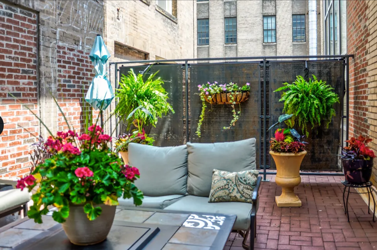a patio with a couch and potted plants