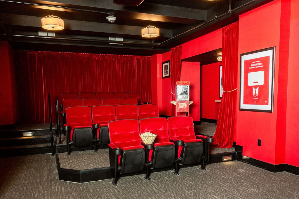 a theater room with red seats and a red curtain