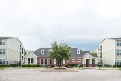 Leasing office exterior image with the parking in front and apartment buildings on both sides.