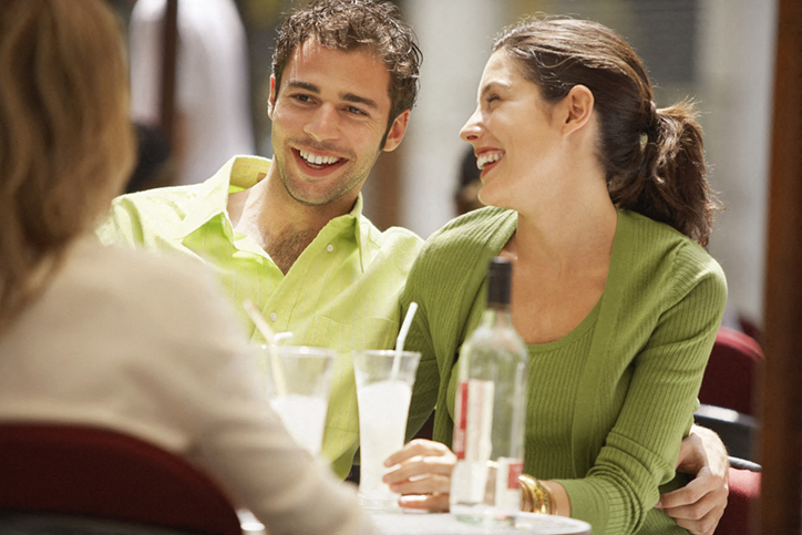 a man and woman sitting at a table with a drink