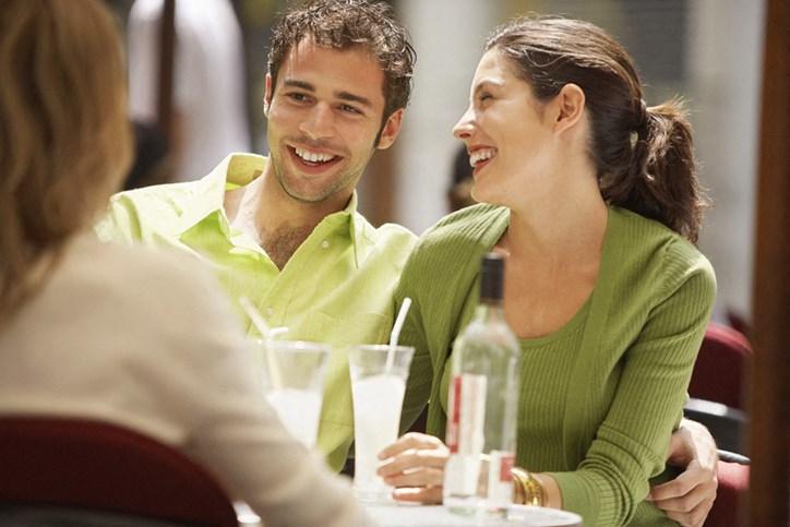 a man and woman sitting at a table with a drink