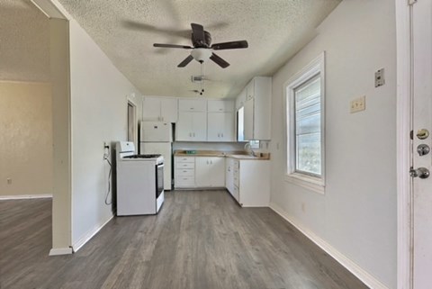 an empty kitchen with white cabinets and a ceiling fan