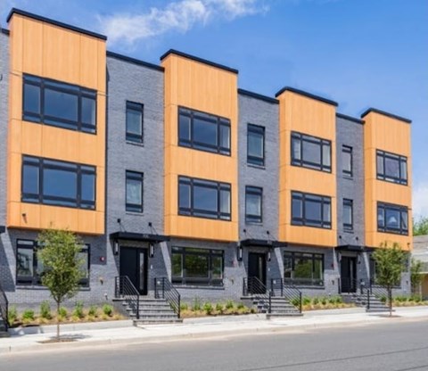 A row of modern townhouses with orange and grey exteriors.