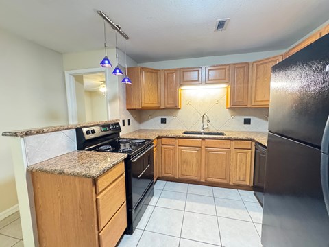 A kitchen with wooden cabinets and black appliances.