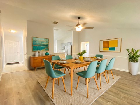 A dining room with a wooden table and green chairs.