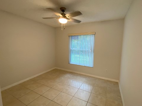 A room with a ceiling fan and a window with blinds.