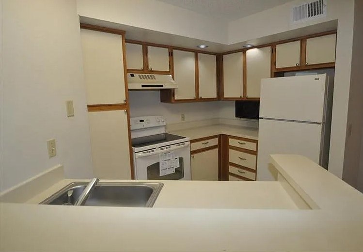 A kitchen with white appliances and wooden cabinets.