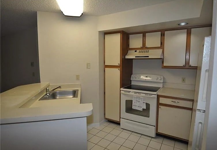 A kitchen with a white sink and white appliances.