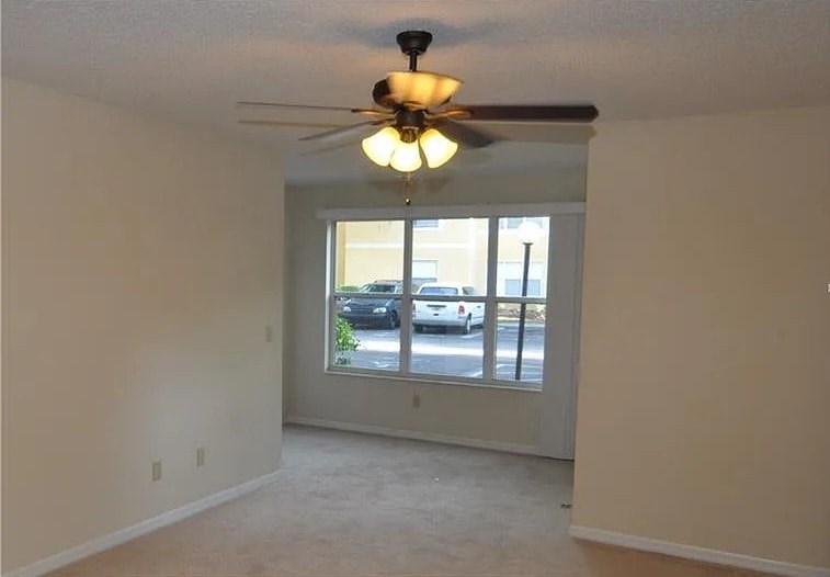 A room with a ceiling fan and sliding glass doors.