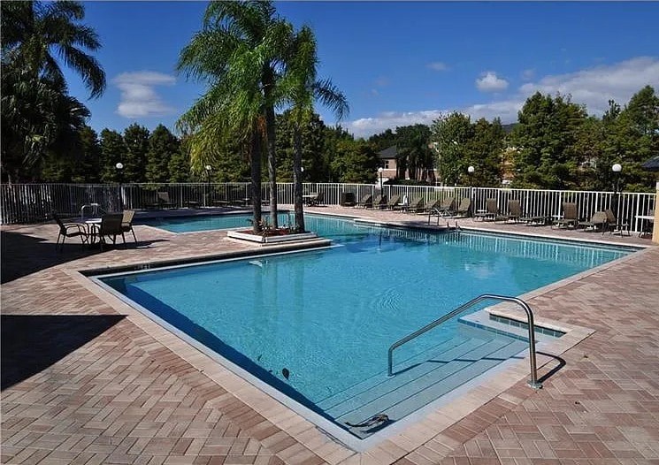 A pool surrounded by palm trees and deck chairs.