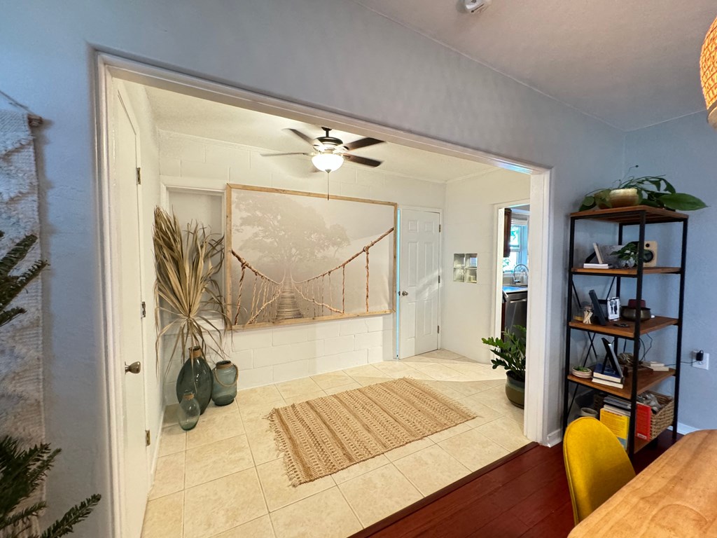 a living room with a ceiling fan and a door leading to a hallway