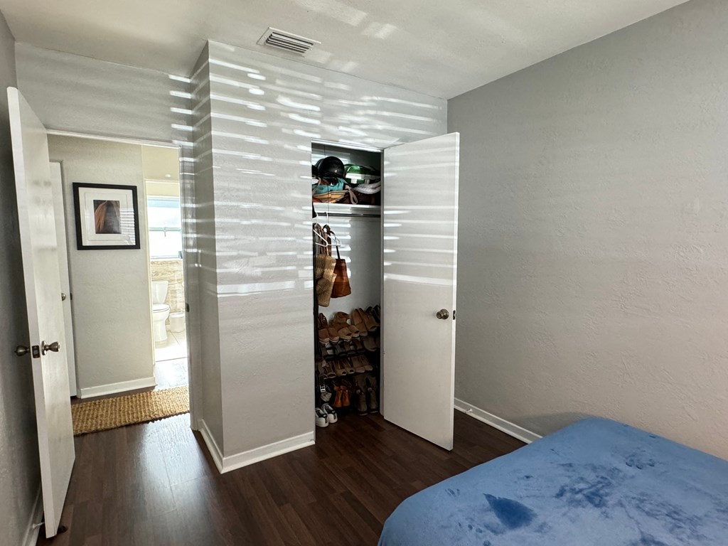 a bedroom with a closet and a bed and a hallway with an open closet door