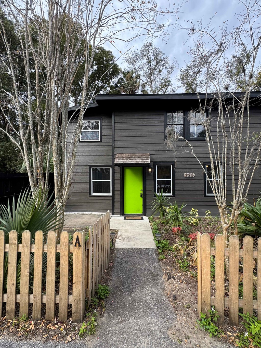 A grey house with a green door and a wooden fence.
