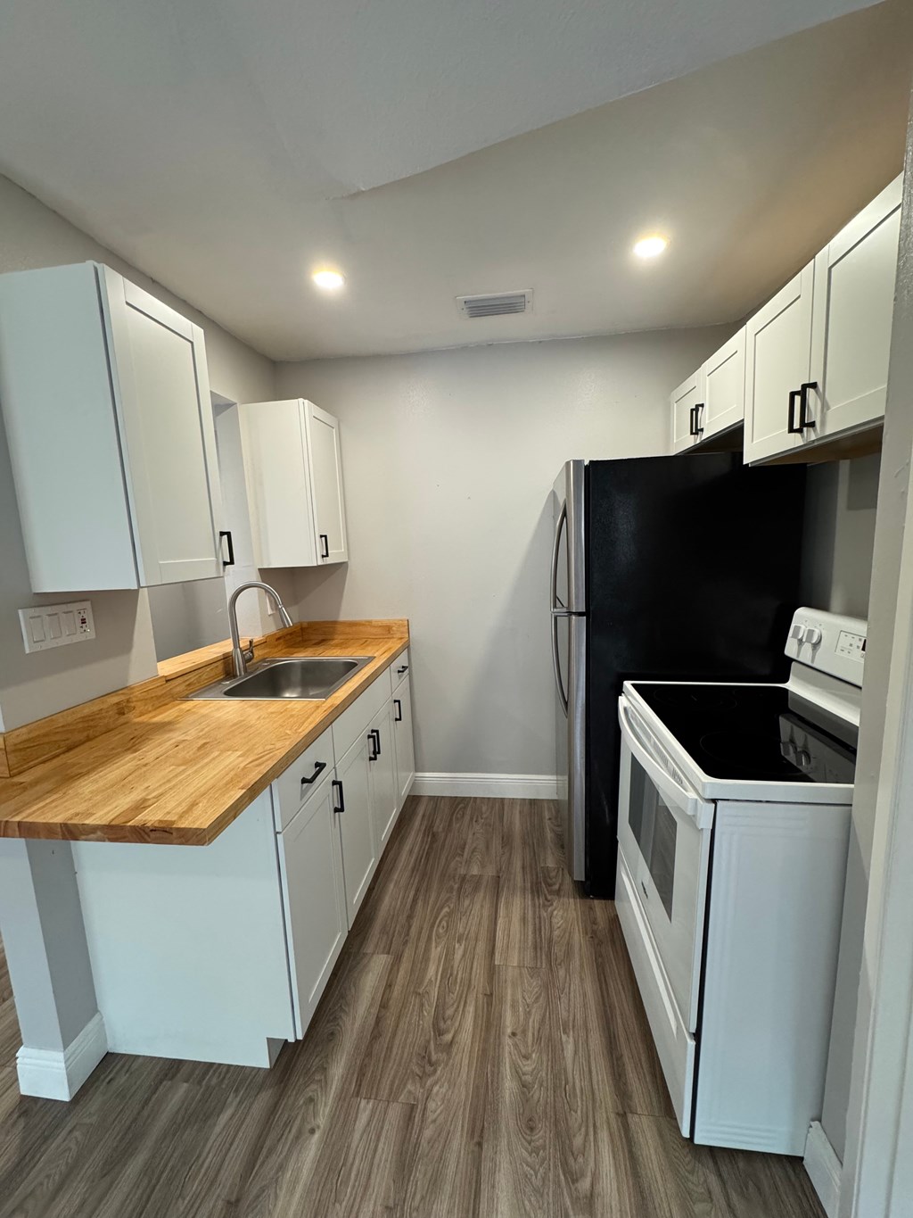 A kitchen with white cabinets and a wooden countertop.