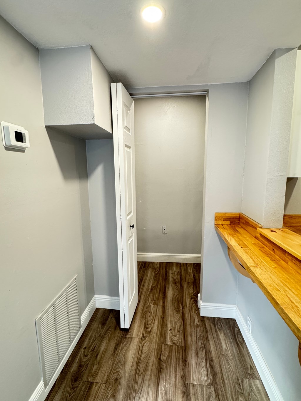 A room with a white door and a wooden floor.