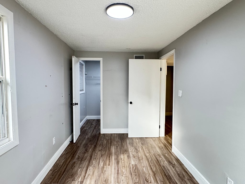 A room with a white door and a window on the left.