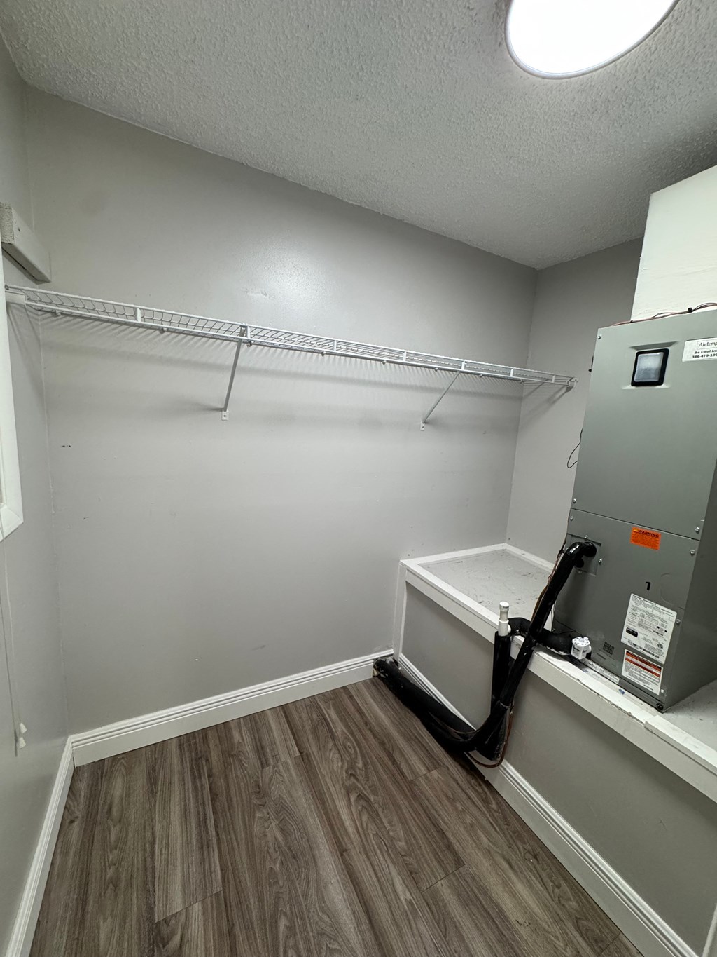 A room with a wood floor and a wall-mounted dryer.