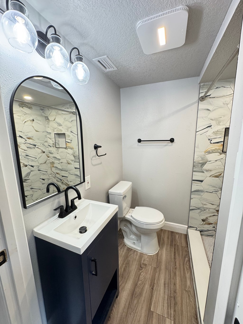 A bathroom with a sink, toilet, and mirror.
