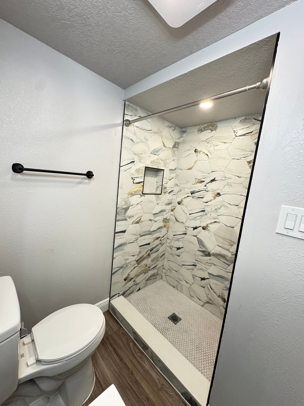 A white toilet with a stone wall behind it.