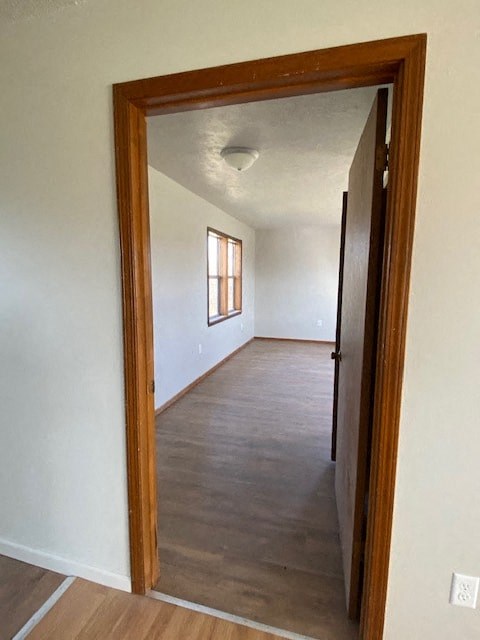A room with a wooden floor and a doorway leading to another room.