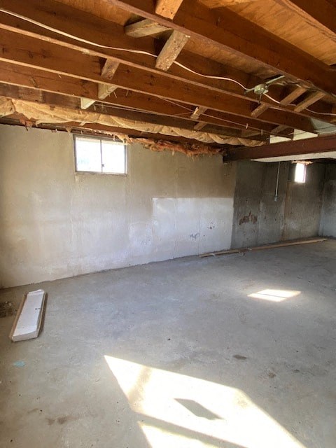 A room with a window and a wooden beam on the ceiling.