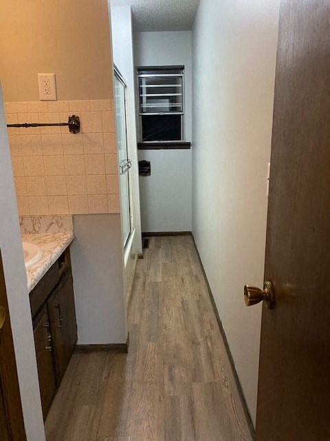 A narrow hallway with a door on the right and a kitchen area on the left.