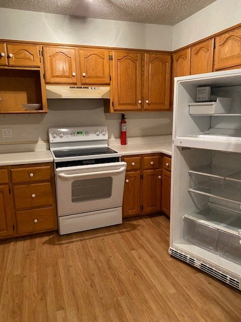 A kitchen with wooden cabinets and a white stove top oven.