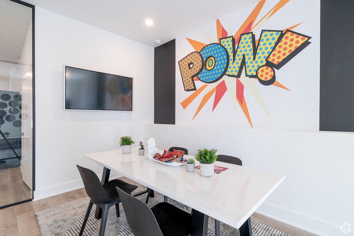 a dining room with a table and chairs and a wall with a pow sign