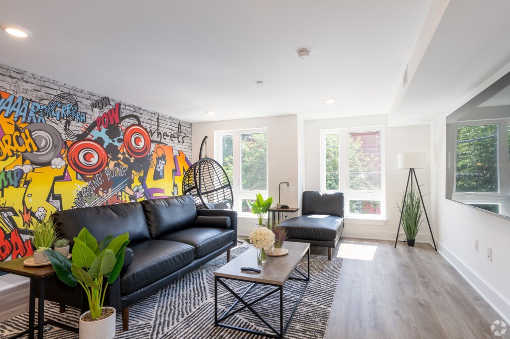 a living room with black leather furniture and a wall covered in graffiti