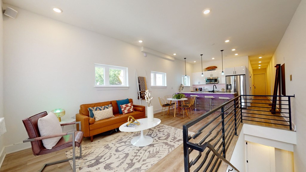 a living room with couches and a table in front of a kitchen
