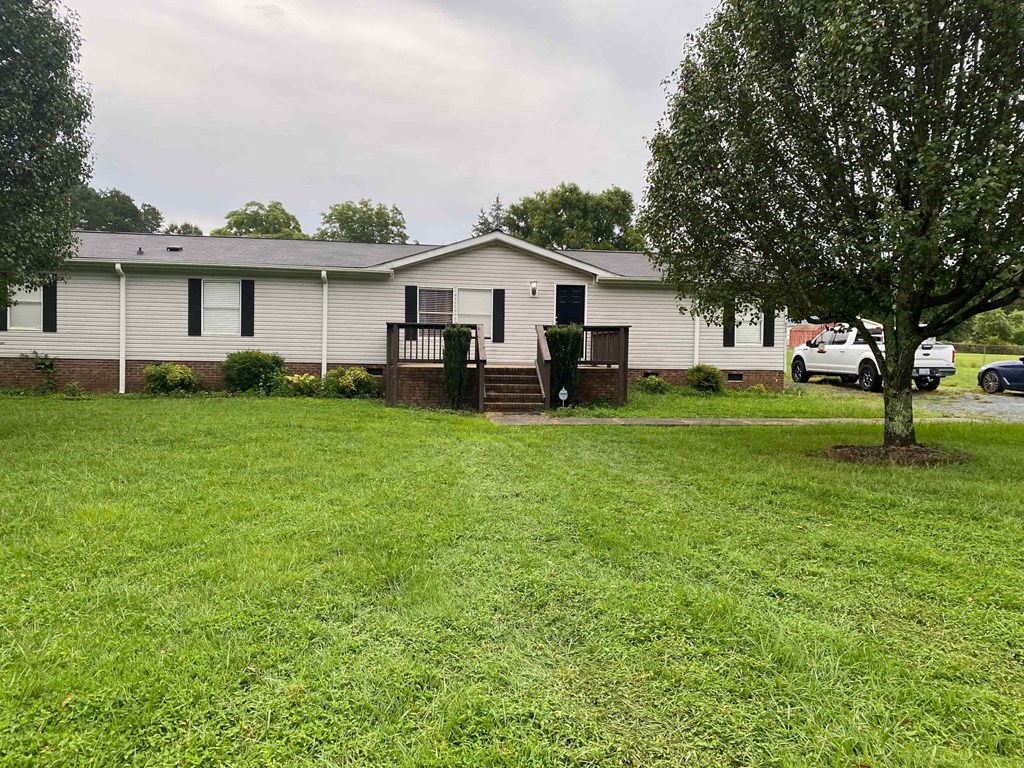 a white mobile home with a yard and a tree