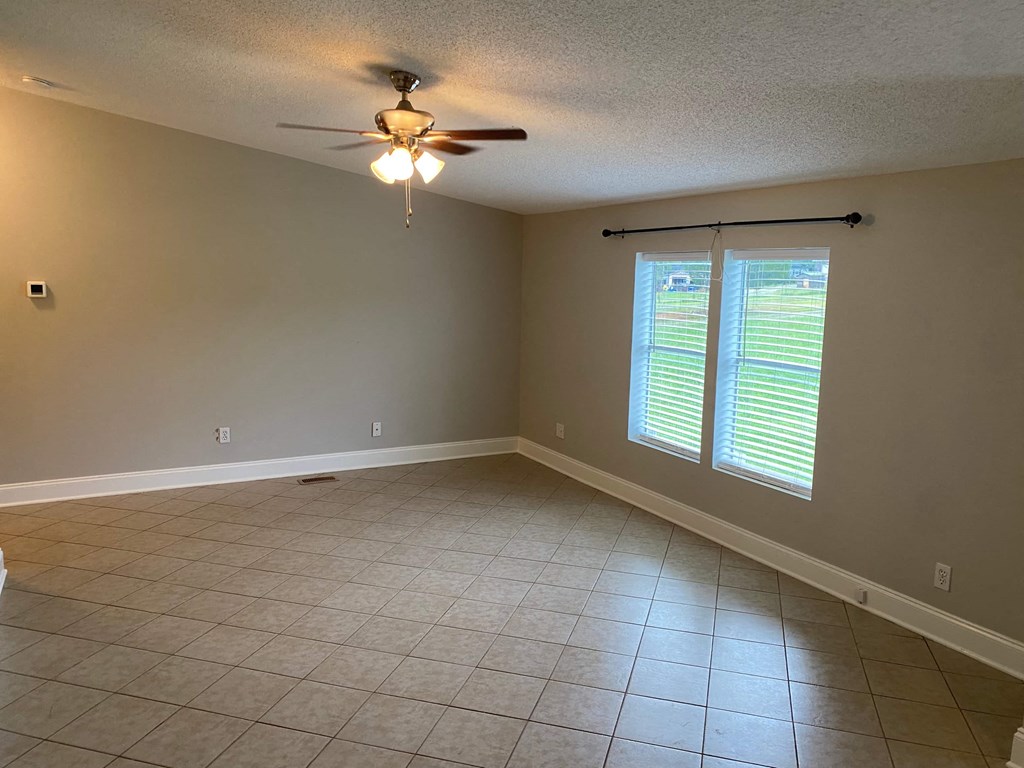 a empty living room with a ceiling fan and a window