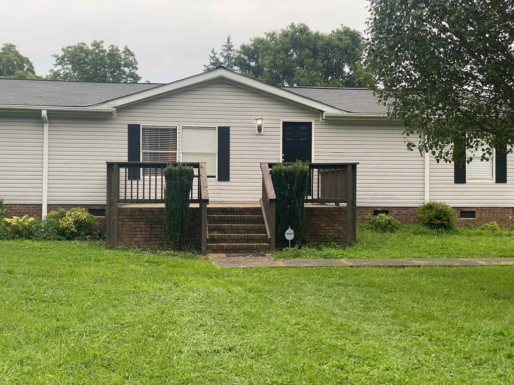a white mobile home with a porch and a yard