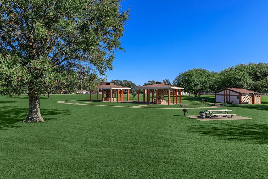 a park with picnic tables and sheds in the grass