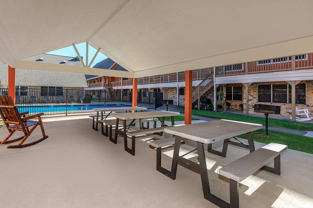 a patio with benches and tables next to a pool