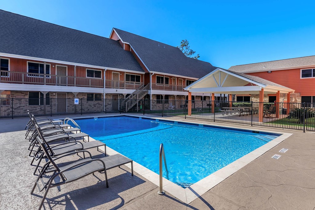 the pool is next to the building of the hotel with chairs
